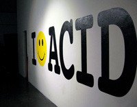 Foto de un cartel blanco con la palabra  I -like ACID en negro. Eñ like, es un emotion.