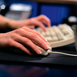 Manos de una persona sobre un teclado y un ratón.