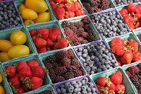 Frutas en cajitas pequeñas en un mercado.