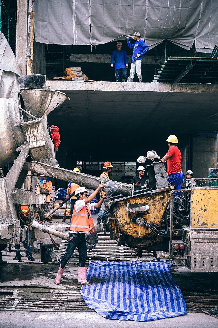 Imagen de varios operadores trabajando con diferente maquinaria en una obra cumpliéndose las normas en material de seguridad y salud en el trabajo. 