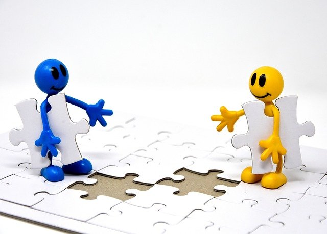 Dos muñecos encajando piezas en puzzle.