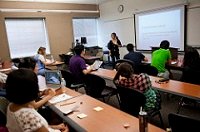Clase donde se ven varios alumnos sentados.